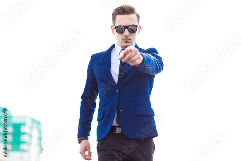 Young busunessman in blue suit and sunglasses stand on the roof photo