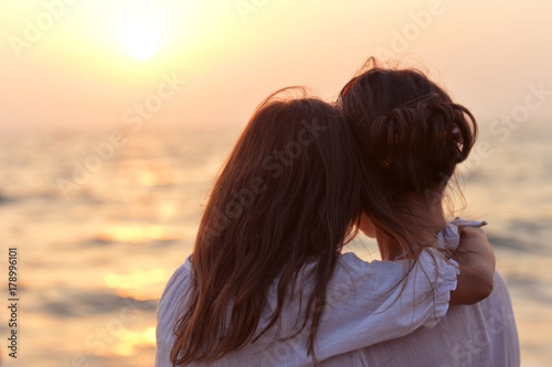 Mother and daughter standing on seashore