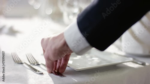 Shot of waiter hand preparing dinner table for celebration at banquet hall