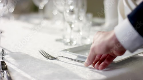 View of waiter hand preparing classy banquet table for celebration at banquet hall