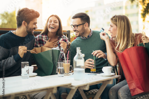 Group of four friends having fun a coffee together after shopping