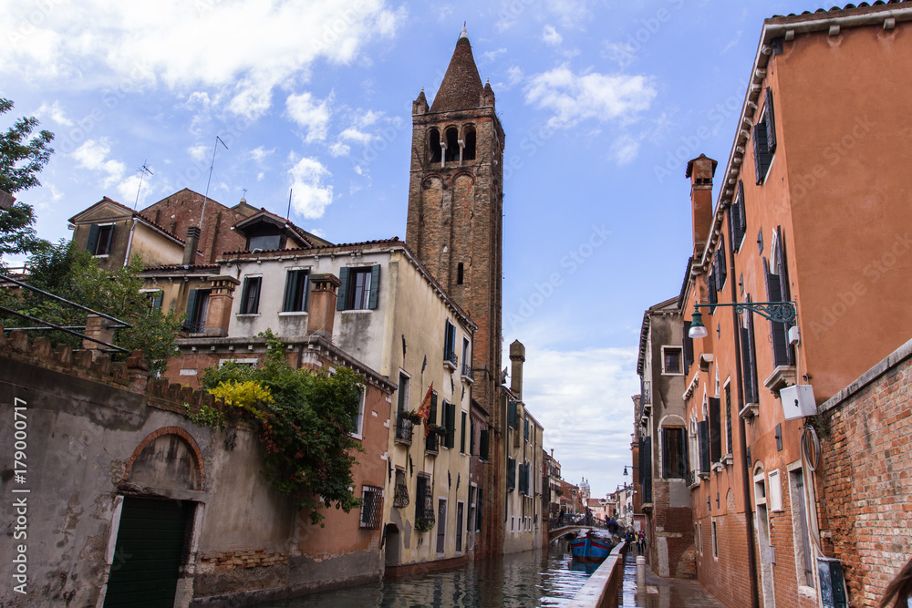 Venetian narrow channel, bell tower and red clay tile roofs, view from the street