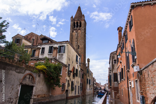 Venetian narrow channel, bell tower and red clay tile roofs, view from the street