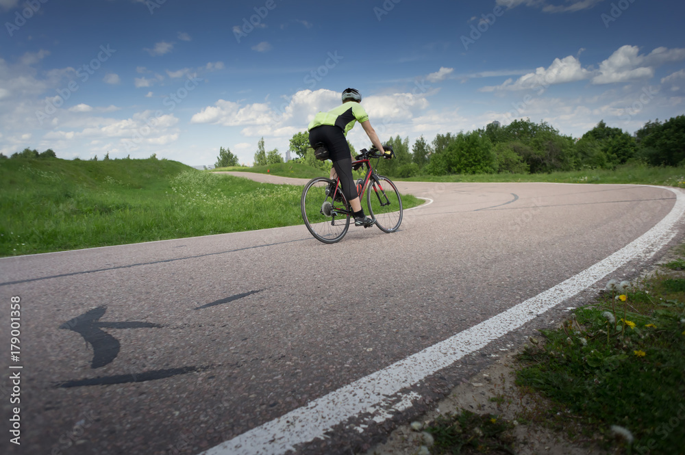 Obraz premium Cyclist racing on the asphalt road at the summer day. blue sky with white clouds