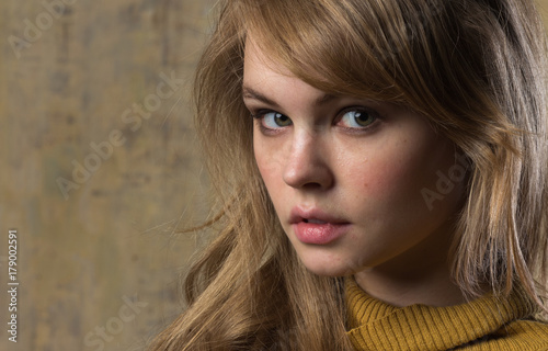 A beautiful young model in a mustard sweater. An image in beige tones.