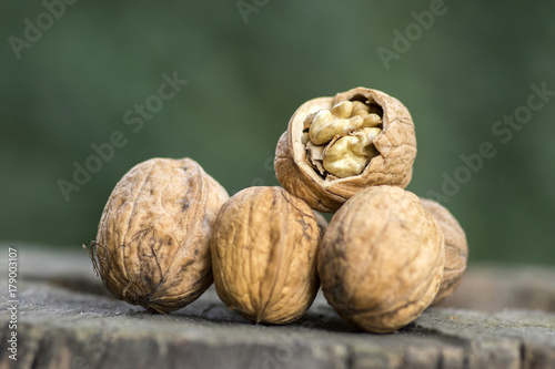 Walnuts in hard shells, pile on wooden tree strump, one broken shell