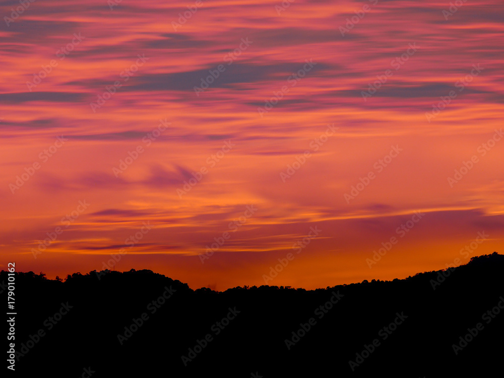 Twilight beautiful evening cloudy sky  after sunset background . There are silhouette mountains and trees.