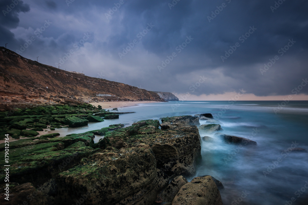 Rocky beach seascape at sunrise. Long exposure from the rocky shore in the Portuguese coast