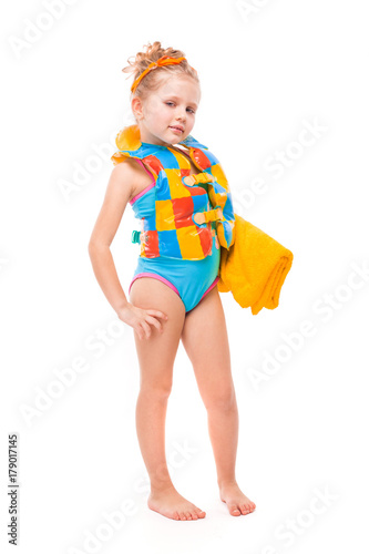 Pretty cute little girl in in blue swimming suit and colorful life jacket hold yellow towel