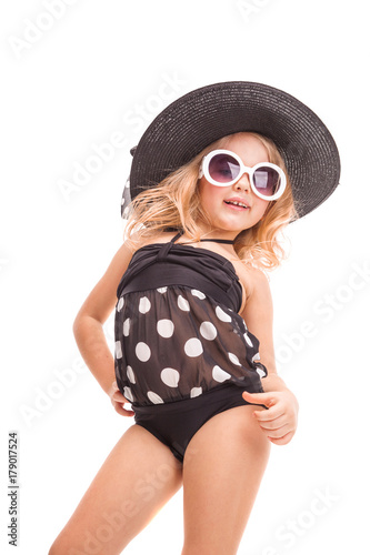Pretty little girl in in black swimwear, white sunglasses and black hat