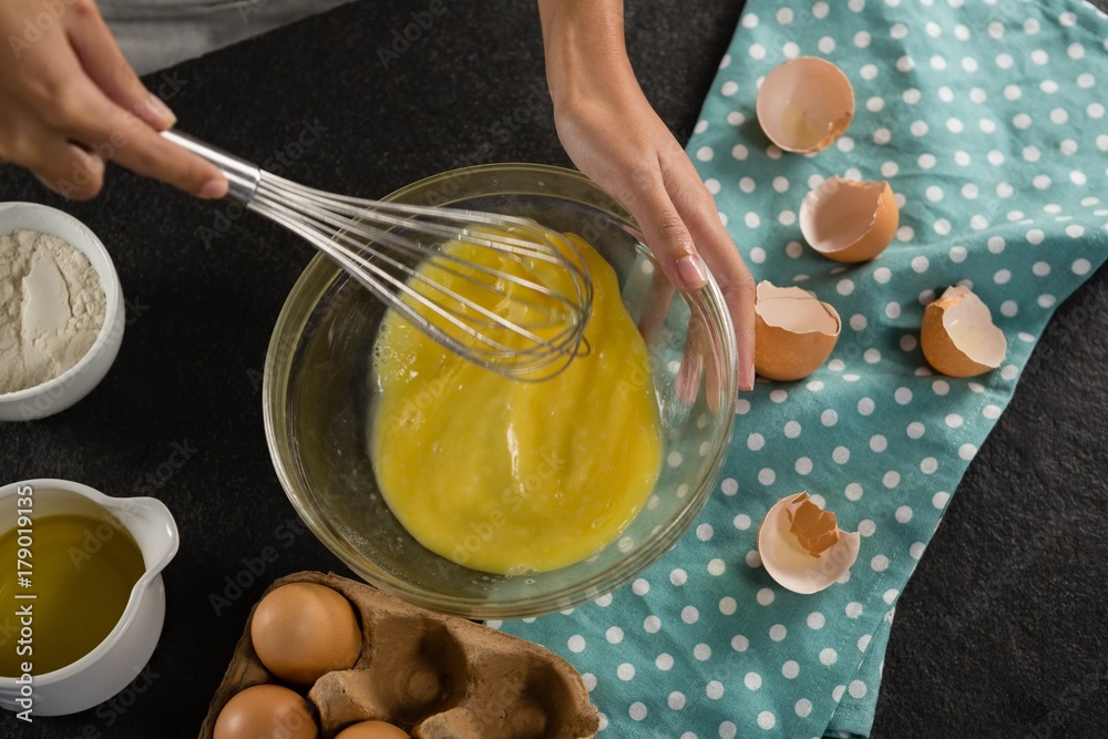 Woman beating eggs with a whisk in a bowl Woman beating eggs with a whisk in a bowl
