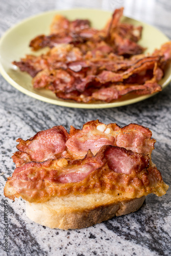 Crisp fried bacon on the bread above grey granite background