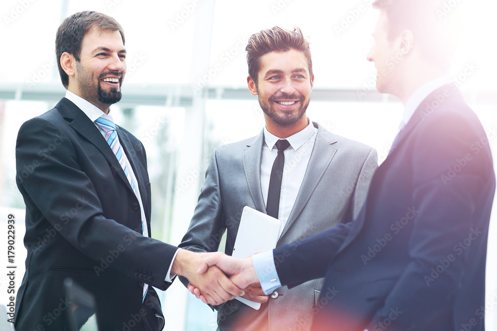 Mature businessman shaking hands to seal a deal with his partner and colleagues in a modern office Mature businessman shaking hands to seal a deal with his partner and colleagues in a modern office