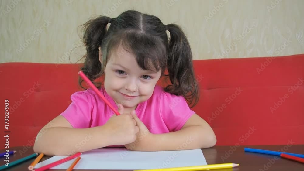A happy child paints with colored pencils. Beautiful little girl with colored crayons. A happy child paints with colored pencils. Beautiful little girl with colored crayons.