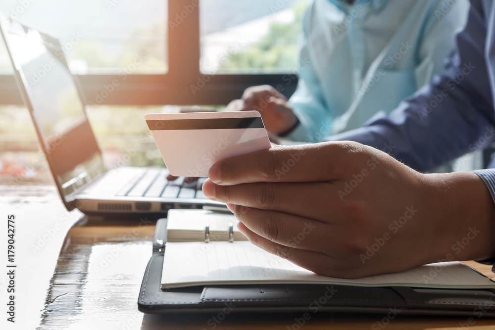 Businessman holding credit card and using laptop. Making payment while online shopping. E-commerce and modern technology concept Businessman holding credit card and using laptop. Making payment while online shopping. E-commerce and modern technology concept