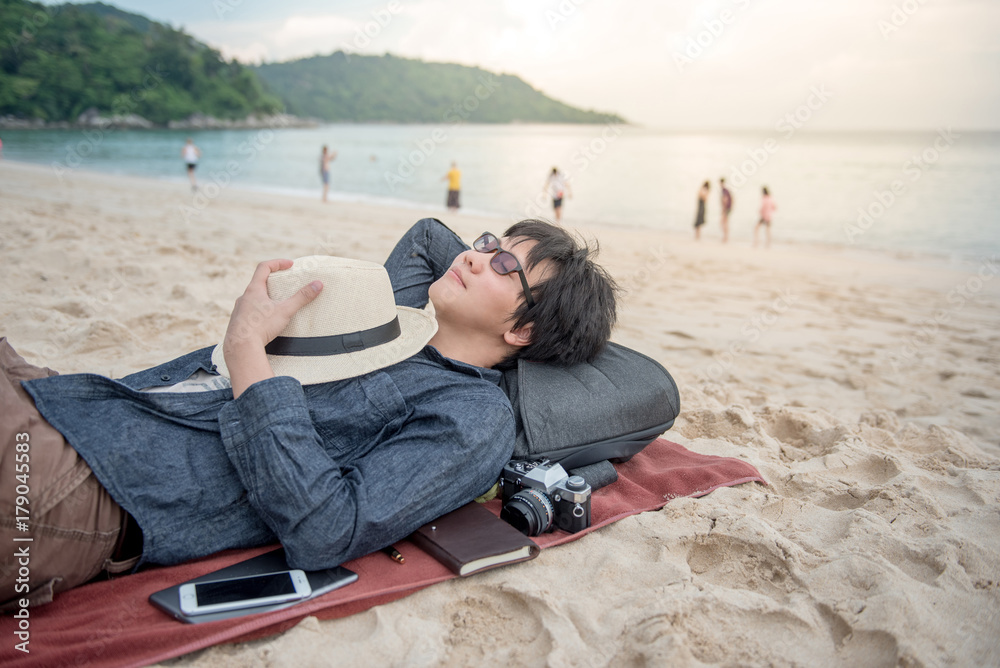 young Asian man lying on the beach, vacation time and summer holiday concepts