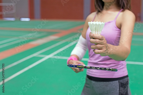 injured woman wearing sportswear painful arm with gauze bandage holding shuttlecock and racket playing badminton, focus on hand