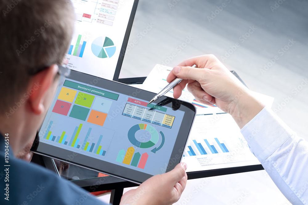 Business colleagues working and analyzing financial figures on a digital tablet Business colleagues working and analyzing financial figures on a digital tablet