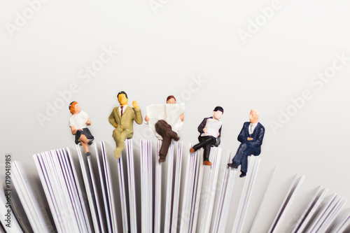 Miniature people sitting on book using as background education or business concept