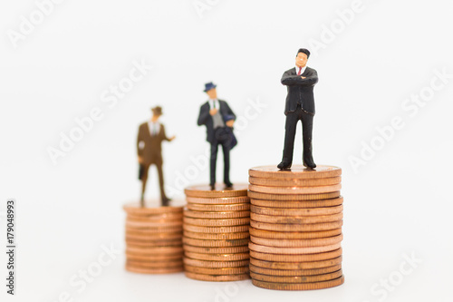 Miniature people: Business man standing on stack of coin using as background Money and financial concepts.