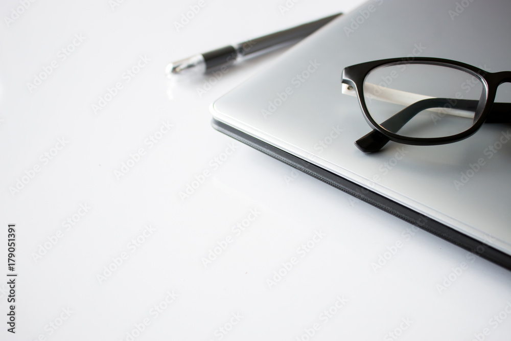 white desk table with office supplies notebook computer and eyeglasses, top view, over light and soft-focus in the background white desk table with office supplies notebook computer and eyeglasses, top view, over light and soft-focus in the background