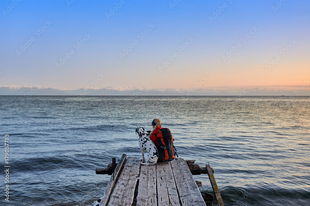 Traveler wearing in warm clothing with backpack enjoying view of sea Traveler wearing in warm clothing with backpack enjoying view of sea