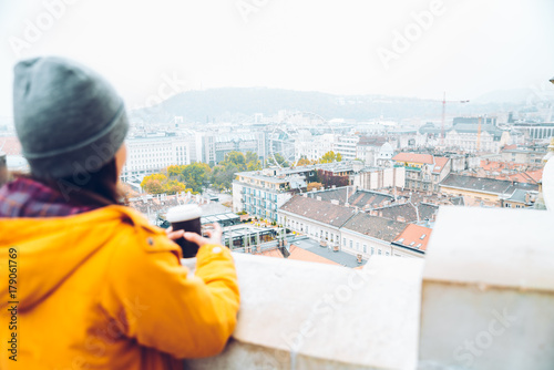 woman with cup of coffe looking at european city
