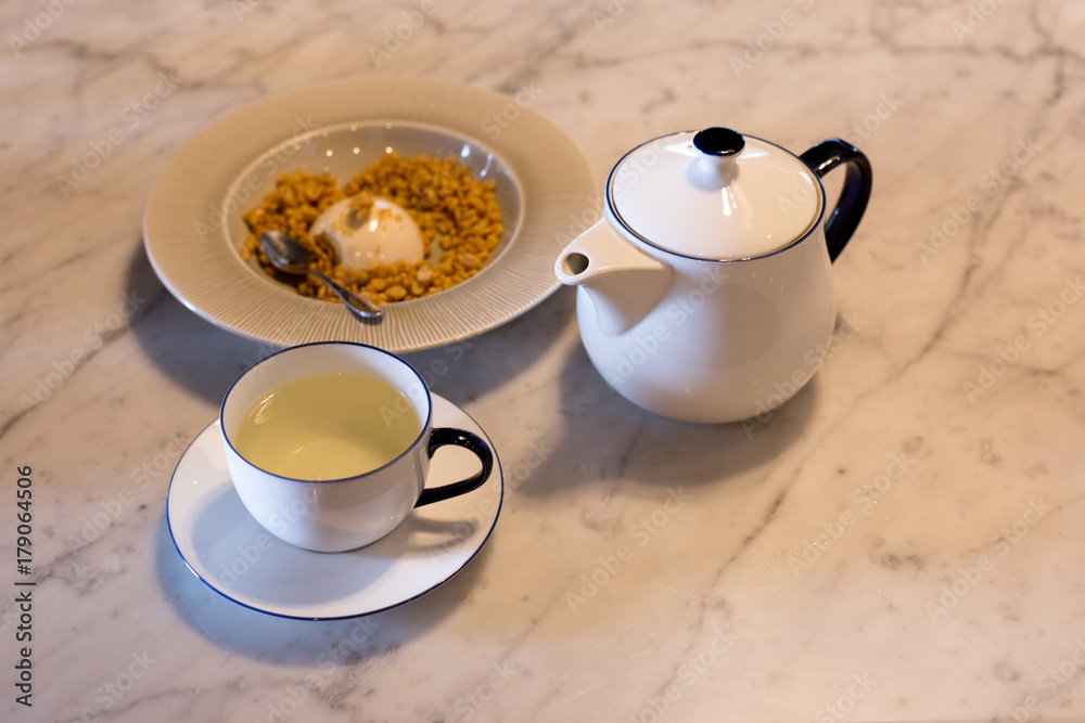 Obraz premium Cup of tea and tea pot with pudding on the table