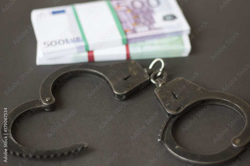 Criminal. Handcuffs on money on black background Criminal. Handcuffs on money on black background