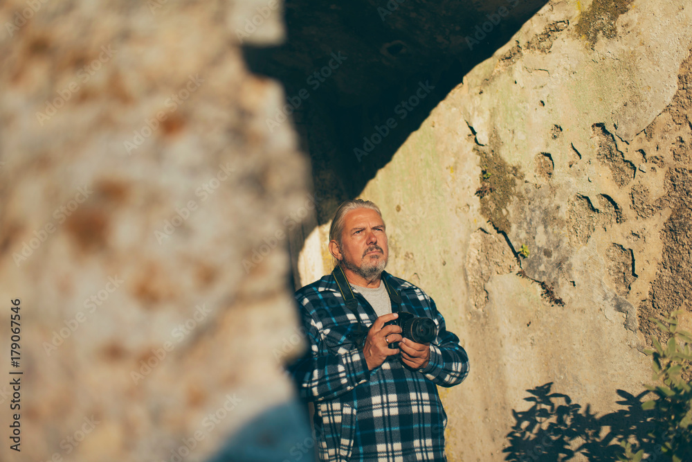 Photographer with gray hair and beard at old building. Old Perithia, Corfu, Greece.