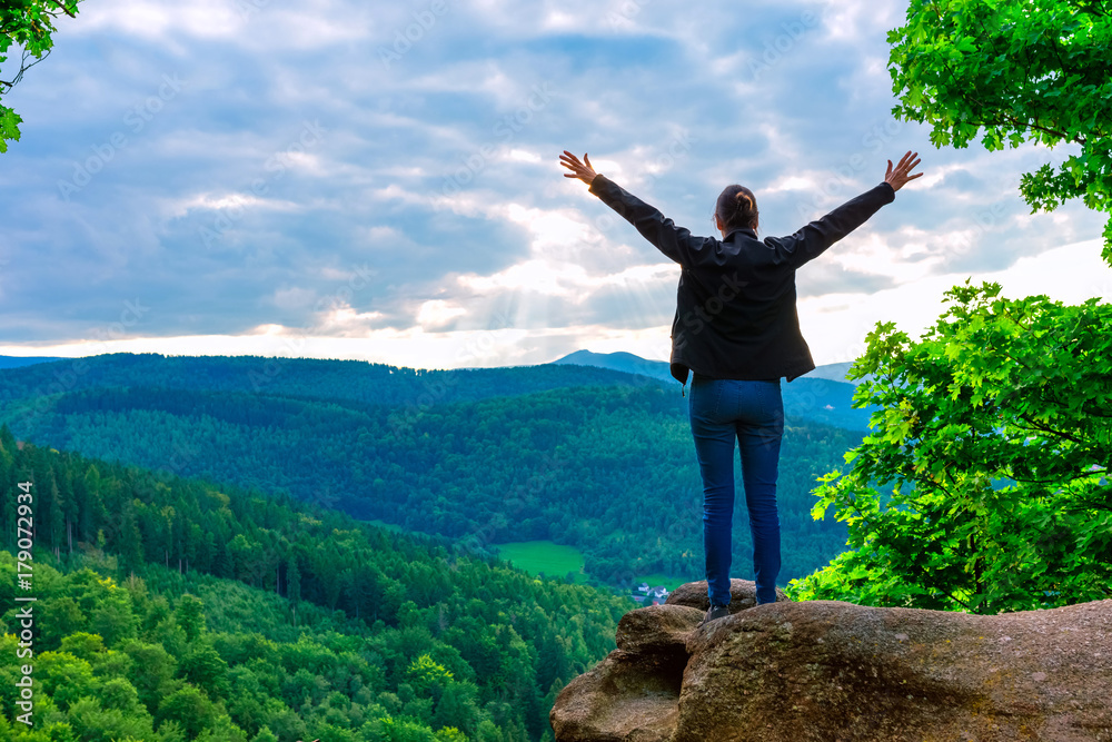 Hiker woman standing with hands up achieving the top, admiring mountain landscape. Epic shot of hiking with cloudy sky, freedom success concept Hiker woman standing with hands up achieving the top, admiring mountain landscape. Epic shot of hiking with cloudy sky, freedom success concept