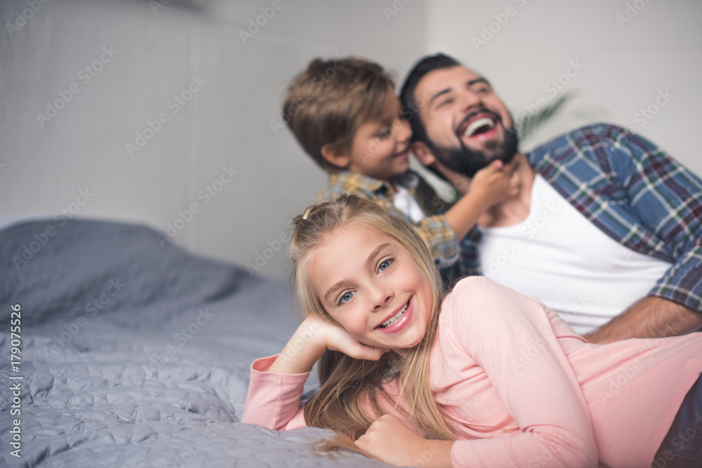 father and kids resting on bed