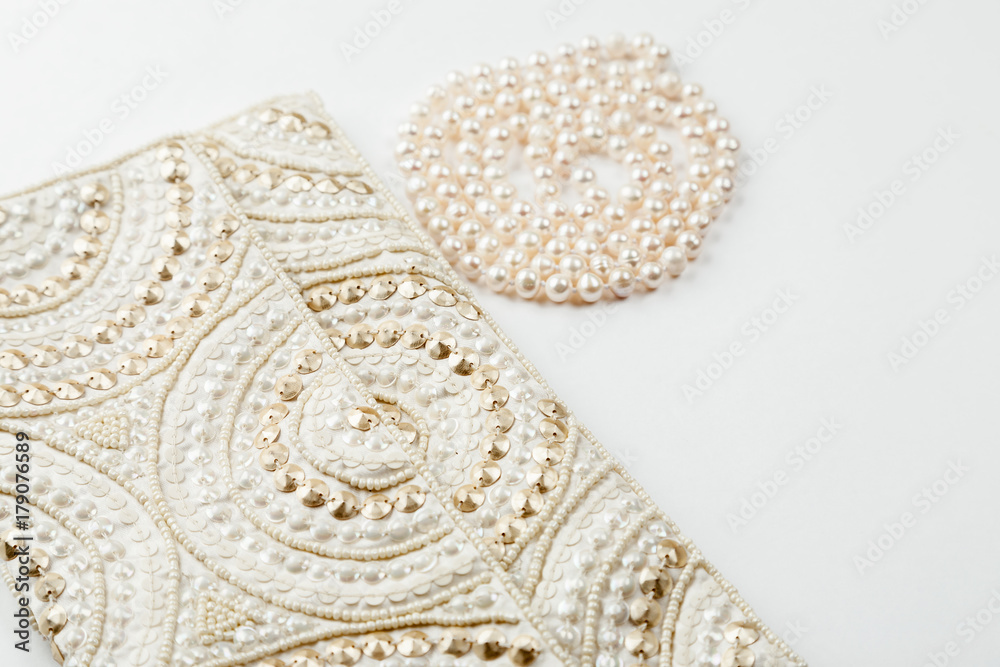 Obraz premium Female white bag and pearl necklace on a white background top view