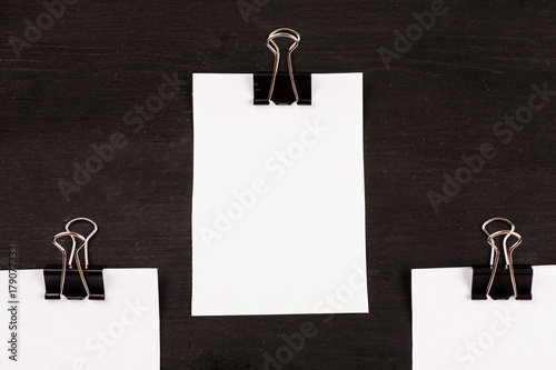 Blank sheets of white paper with paper clip on a black background