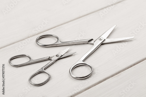 Big and small metal scissors on a white wooden table
