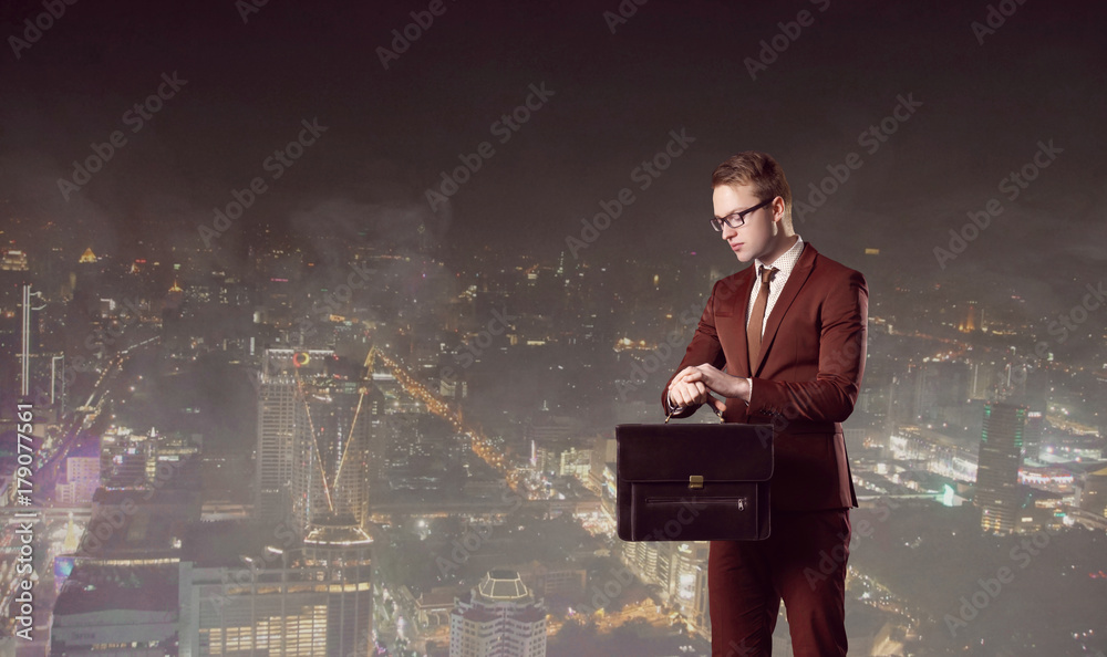 Businessman with briefcase standing on a night city background. Job, business, career, concept. Businessman with briefcase standing on a night city background. Job, business, career, concept.