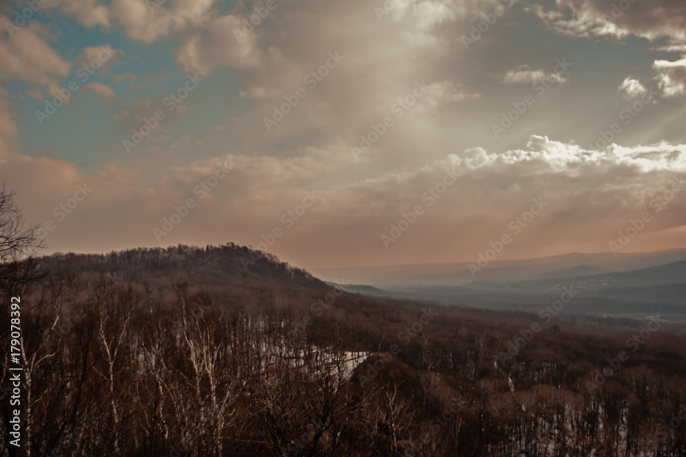 mountain peaks in a foggy air and sunrays seen through the clouds mountain peaks in a foggy air and sunrays seen through the clouds