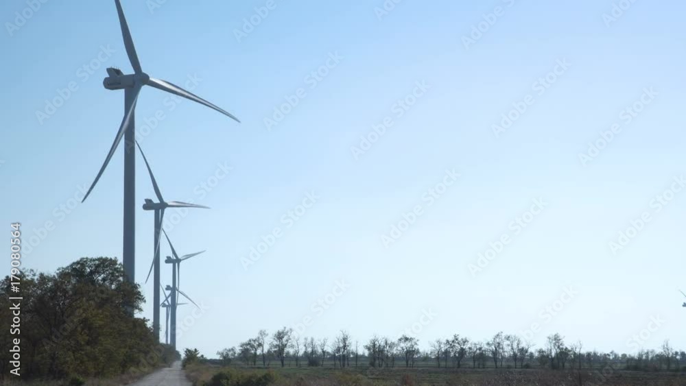 Turbines spinning on wind farm against clear sky Turbines spinning on wind farm against clear sky
