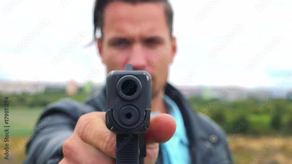 A criminal points a gun at the camera - closeup A criminal points a gun at the camera - closeup
