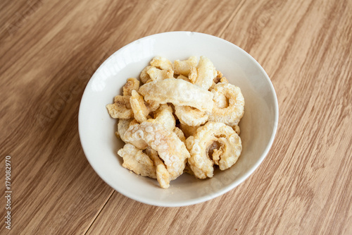 Fried pork rince or Crispy pork skin in white bowl on the wood table, North Thailand food cook from prok skin to fried