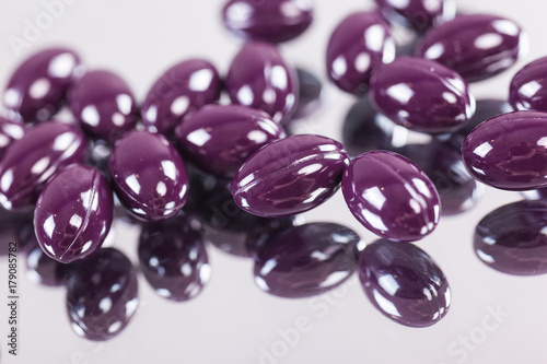 capsules purple pills closeup on mirror surface