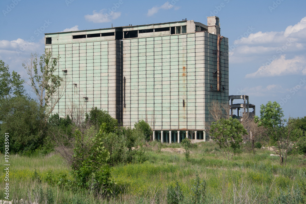 Abandoned grain elevator in overgrown field Abandoned grain elevator in overgrown field