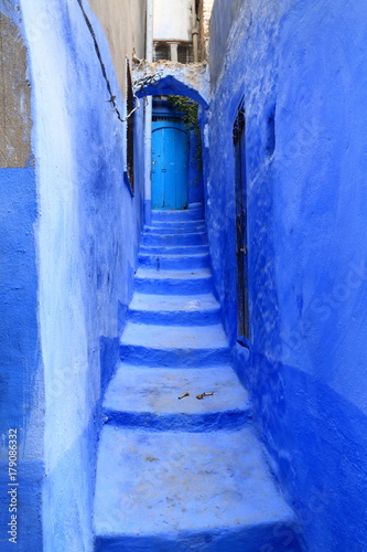Blue door at the end of a narrow alley with steps, in Chaouen, Morocco © juanorihuela