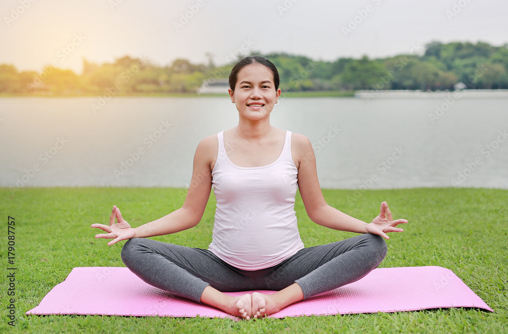 Pregnant woman doing yoga in the public park.