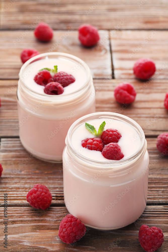 Raspberries yogurt in jars on brown wooden table Raspberries yogurt in jars on brown wooden table