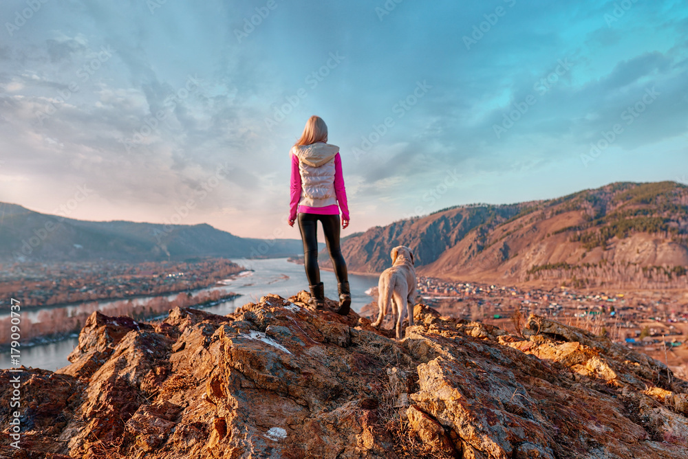 Fototapeta premium the girl with the dog looking into the distance in the spring in cold