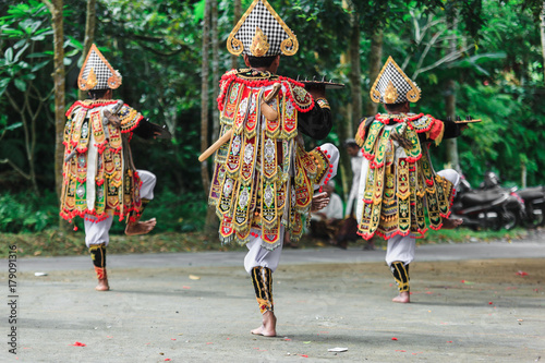 Men in traditional costumes perform a Balinese war dance called Tari Baris Gede outdoors. Back view. photo