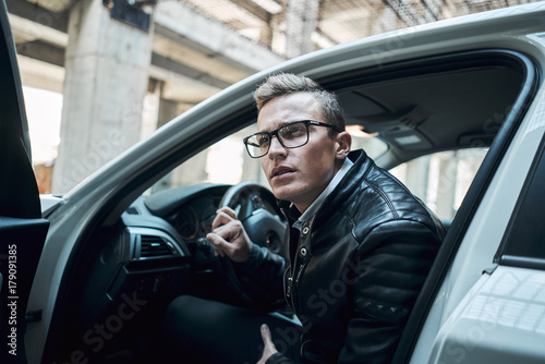 Close-up. Young handsome man looks out of a white car © Bogdan