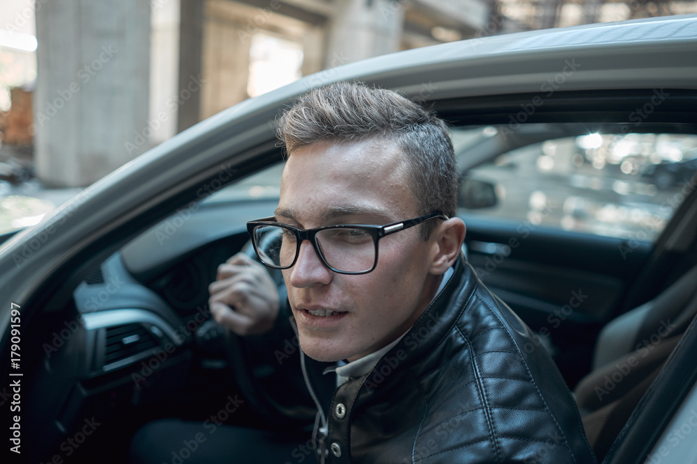 Close-up. Young handsome man looks out of a white car