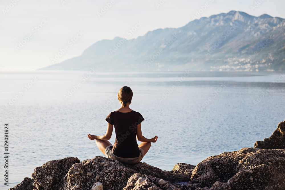 Young woman practicing yoga near the sea. Harmony and meditation concept. Healthy lifestyle